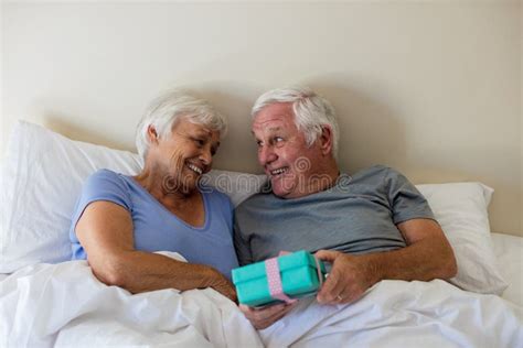 Senior Man Giving A Surprise T To Woman In The Bedroom Stock Image Image Of Closeness