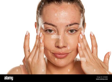 Young Woman Applying Concealer Under Her Eyes With Her Fingers On White