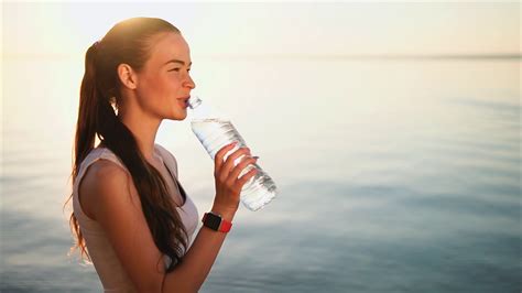 Young Brunette Woman Drinking A Clean Water From The Plastic Bottle