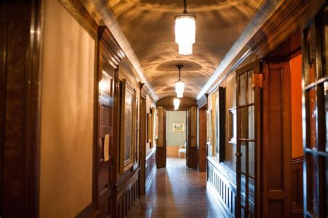 A Long Hallway With Wooden Doors And Lights On Either Side Of The