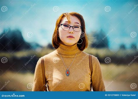 Portrait Of A Beautiful Ginger Haired Asian Woman With Glasses On Her Face Dressed In A Yellow