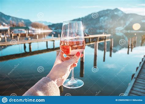 Female Hand With Glass Of Rose Wine Cozy Pier On The Coast Of The Lake