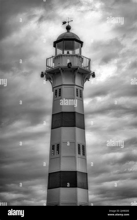 A Vertical Grayscale Of A Lighthouse Against A Dramatic Cloudy Sky