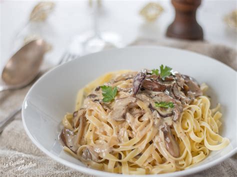 A white bowl filled with pasta covered in mushrooms and parsley on top