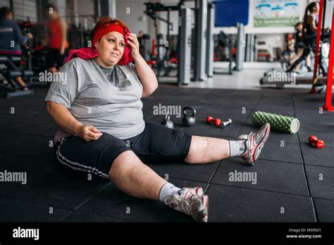 assez grosse femme est assise sur le sol dans la salle de sport calories de brûlure de femmes