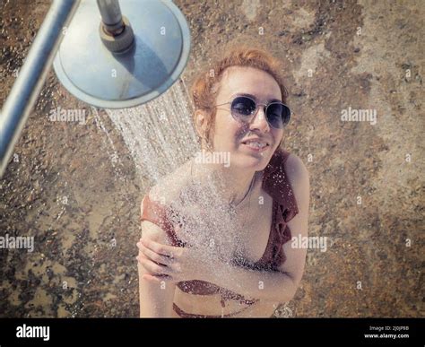 Das Mädchen mit Sonnenbrille und Bikini wäscht sich unter der Dusche im