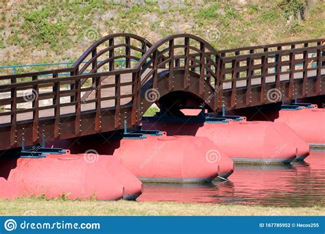 Floating Wooden Pontoon Bridge With Strong Red Floats And Center Arch