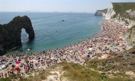 People Enjoying The Good Weather On The Beach At Durdle Door Near