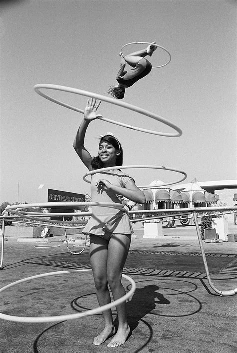a woman in a bathing suit holding two hula hoop s while standing on the ground