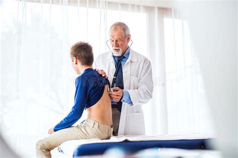 Senior Doctor Examining A Small Boy In His Office Stock Image Image