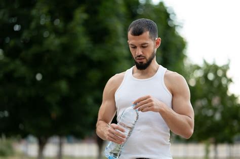 Premium Photo Sporty Young Man Drinking Water In Park In Summer
