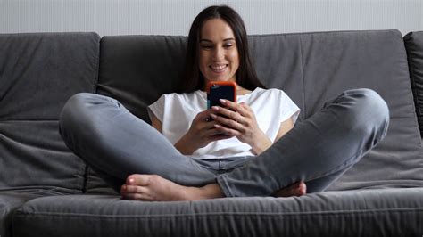 Woman With Crossed Legs Sitting On The Sofa With Telephone Stock Video