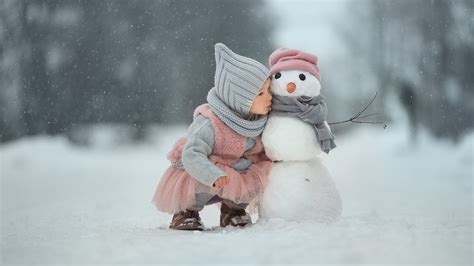 Little Girl Is Sitting On Snow In Snow Field Background Wearing Woolen