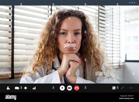 Serious Female Doctor Carefully Listening And Keeping Hands Under Chin