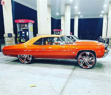 An Orange Car Parked In Front Of A Gas Station