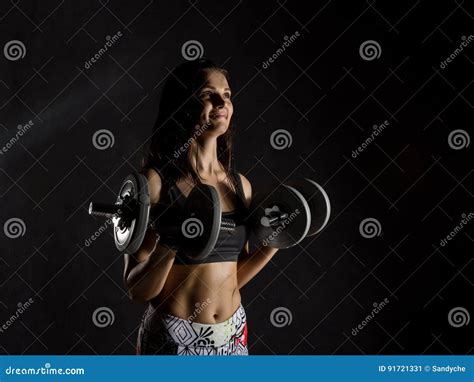 Fitness Girl With Dumbbells On A Dark Background Athlete Doing Exercises In The Gym Stock Image