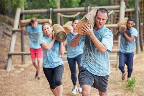Determined People Running With Logs On Boot Camp Obstacle Course