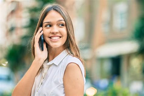 linda adolescente latina sorrindo feliz falando no smartphone da cidade imagem de stock imagem