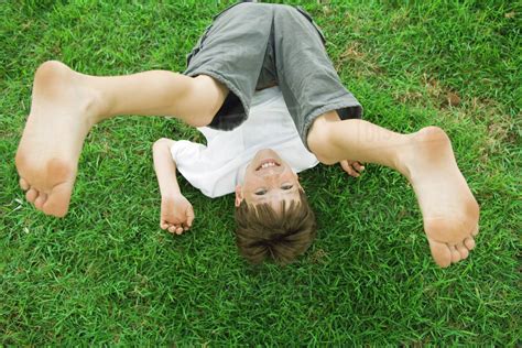 Boy Lying On The Ground With Legs In The Air Smiling At Camera High Angle View Stock Photo