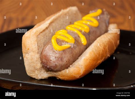 Cooked Bratwurst On A Bun Topped With Mustard Stock Photo Alamy
