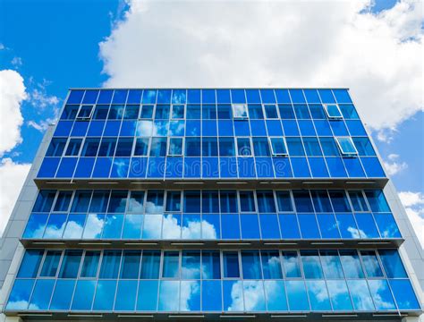 Facade Of A Modern Building Glass Windows Reflected The Sky And Clouds