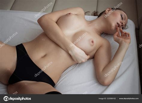 Sensual encantadora mujer desnuda en lencería acostada en la cama en la habitación fotografía