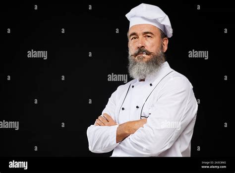 Professional Waist Up Portrait Of Bearded Senior Chef Posing Against Black Background Standing