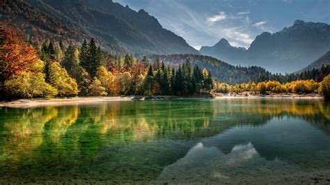 Calm Body Of Water Surrounded With Trees And Mountains During Daytime