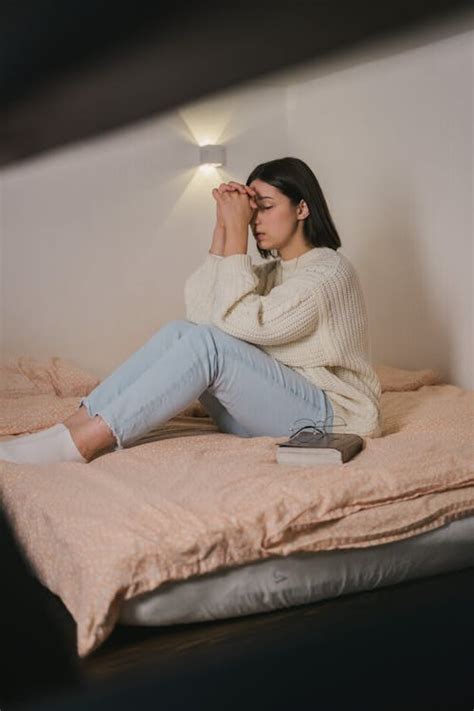 Woman In White Sweater And Blue Denim Jeans Sitting On Bed · Free Stock