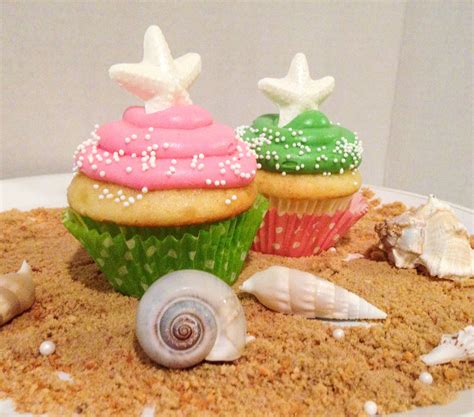 Three Cupcakes With Sprinkles And Sea Shells On A White Plate