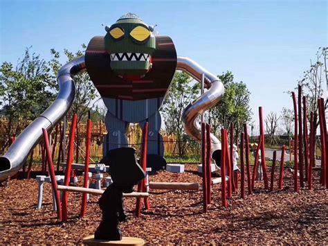 A Playground With An Inflatable Monster On Its Back And Lots Of Red Poles