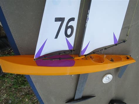 An Orange And Purple Sail Boat With Numbers On Its Side Next To A