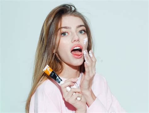 Surprised Pretty Girl Putting Facial Cream Or Mask On Face Beauty