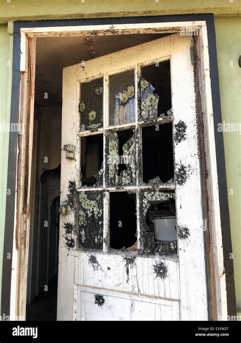 Front Door Of Abandoned House With Broken Glass Windows And Paintball