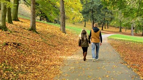 Young Man And Woman Walking In The Park Hand In Hand Stock Footage