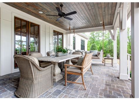 Vertical frame brown wooden bench swing at the porch of a home with pastel blue front door. Southern Living Idea House outdoor porch with rustic table ...
