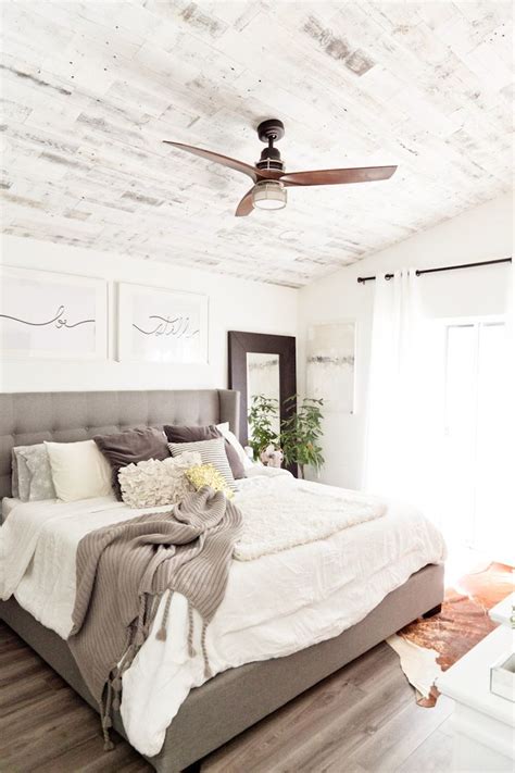 A Bedroom With A Bed Ceiling Fan And Pictures On The Wall Above It S Headboard