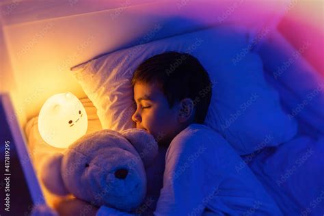 Little Preschool Kid Boy Sleeping In Bed With Colorful Night Led Lamp