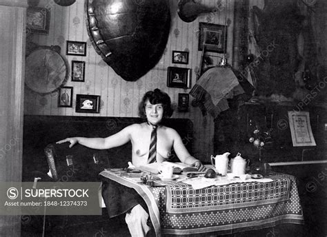 Woman With Naked Upper Body Wearing A Tie Sitting At A Dining Room