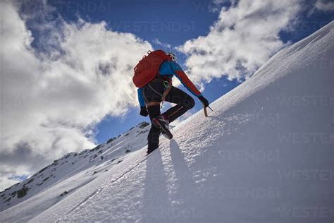 Man Climbing A Snowy Mountain On A Sunny Day In Devero Italy Stock Photo