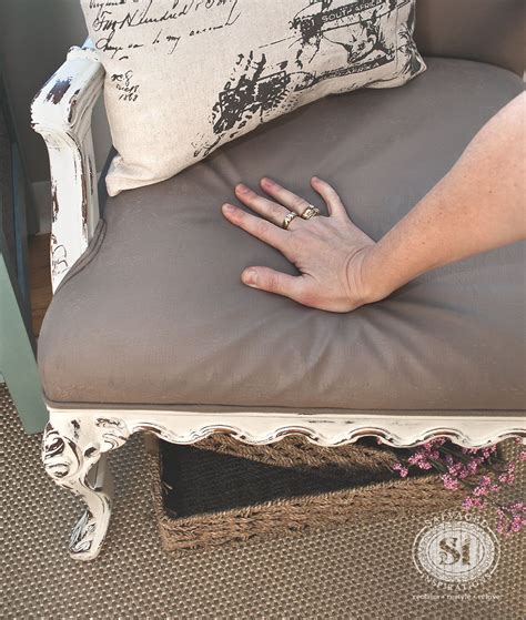 A Persons Hand Resting On The Arm Of A Chair With A Pillow Over It