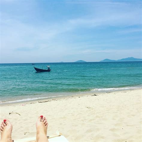 A Person Laying On Top Of A Beach Next To The Ocean With A Boat In The Background