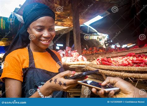 Young Black Woman Selling Tomatoes In A Local African Market Receiving
