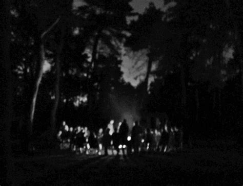 Black And White Photograph Of People Walking In The Woods At Night