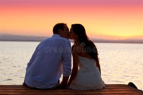Couple Kissing At Sunset Sitting In Jetty At Orange Sea Lake Ad