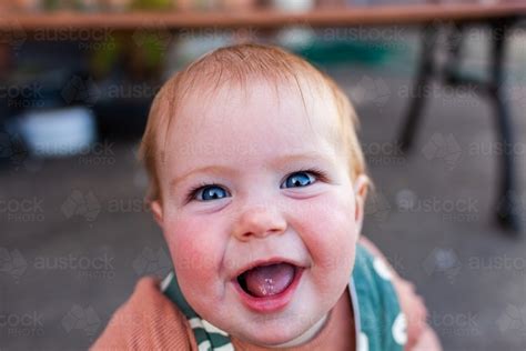 Image Of Bright Blue Eyes And Huge Smile On Baby Playing Outdoors