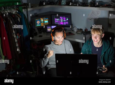 Excited Teenage Boys With Headphones Playing Video Game At Computer In