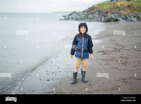 Boy Enjoying The Rain And Having Fun Outside On The Beach A Gray Rainy