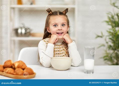 Little Girl Eating Breakfast Cereal With The Milk In The Kitchen