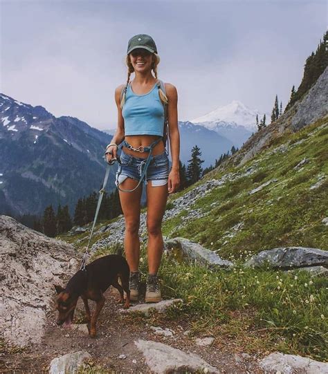 A Woman Hiking With Her Dog On A Mountain Trail In The Mountains While